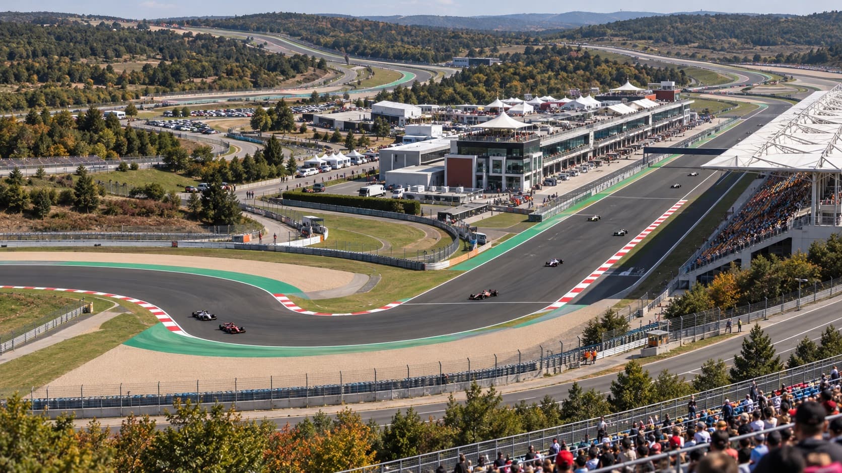 Illustrative aerial view of a racing circuit, grandstands and open-wheel cars in wooded hills